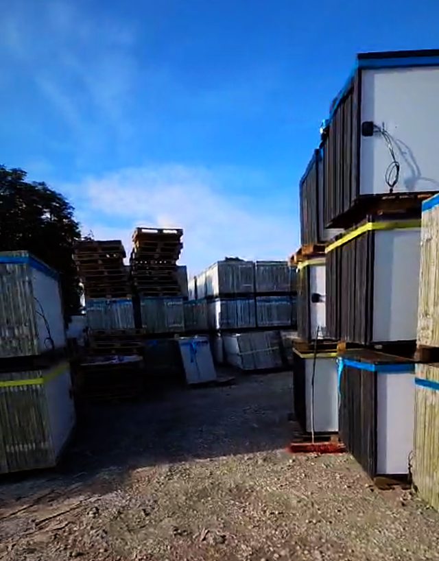 Gänge zwischen gestapelten Paletten mit Solarmodulen auf dem Lagerplatz